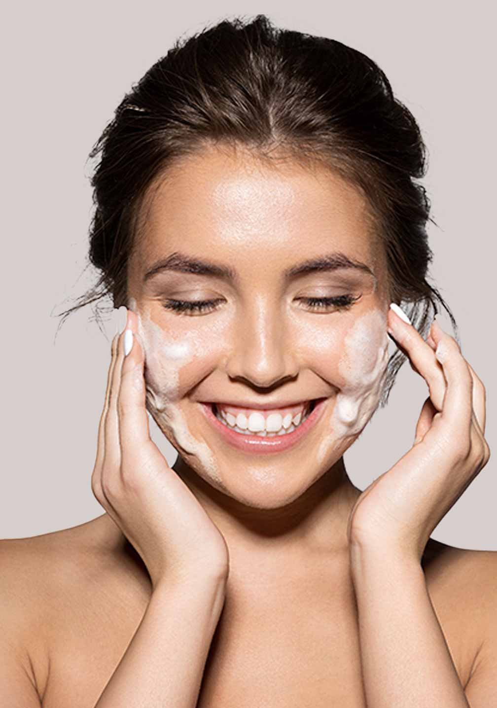 Junge Frau mit sauberer, natürlicher Haut benutzt die Beyond Active Herbal Cleansing Foam von RAU Cosmetics.