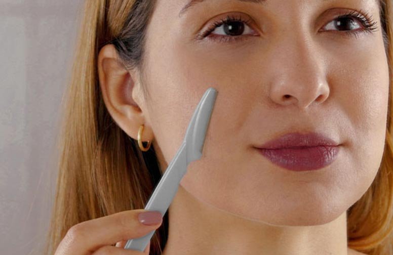 Frau mit Gesichtsrasierer, der Dermaplaning-Technik anwendet, um abgestorbene Hautzellen und feine Härchen zu entfernen.