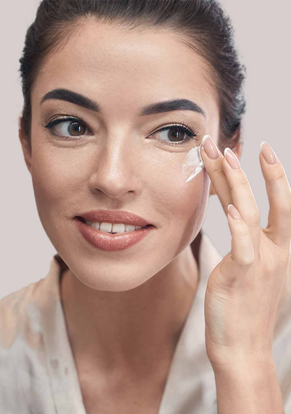 Frau trägt RAU Cosmetics Caviar Eye Cream auf, um ihre strahlende Haut zu pflegen.