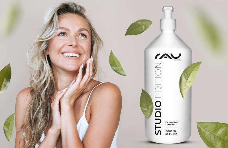 Frau mit glänzendem Lächeln, hält die RAU Cosmetics STUDIO EDITION Reinigungslotion in weißem Flakon.