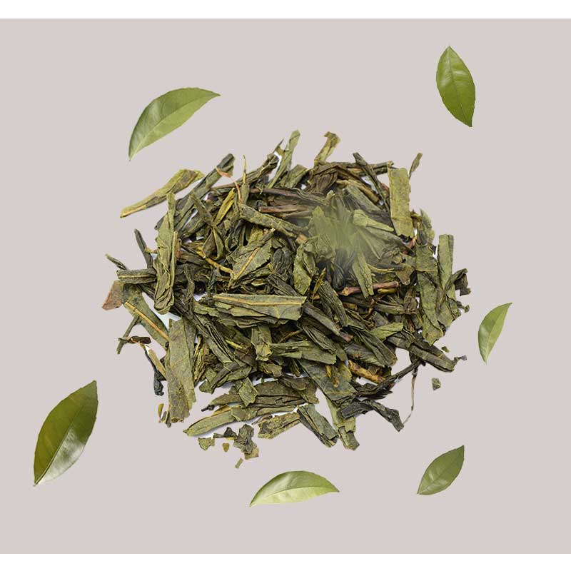 greuner-tee Grüner Tee Blätter und frische Teeblätter auf grauem Hintergrund, symbolisierend die natürlichen Inhaltsstoffe des RAU Tri-Peelings für Hautregeneration und Anti-Aging.