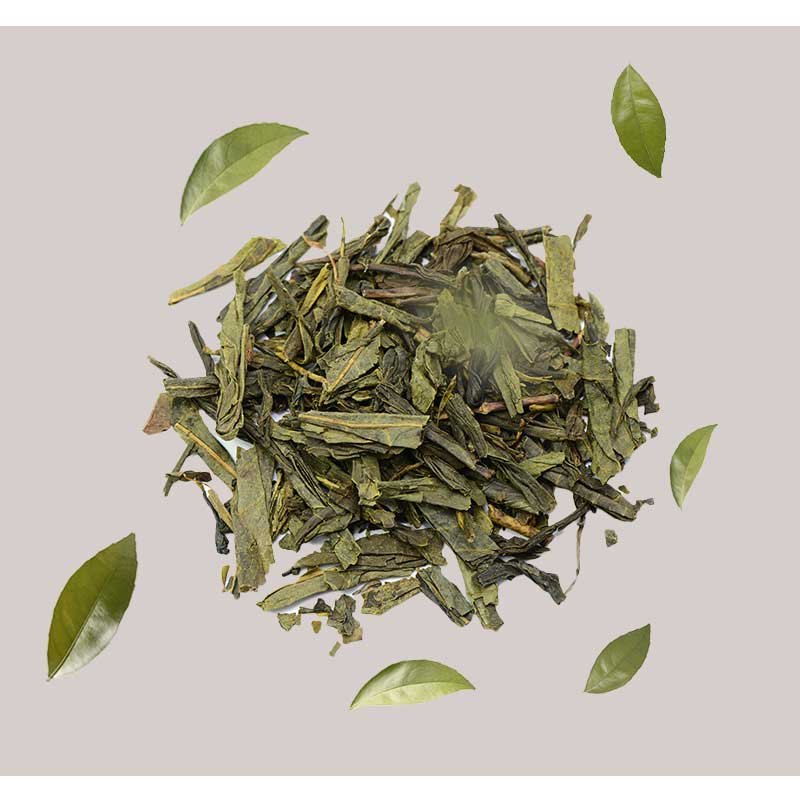 Grüner Tee Blätter und frische Teeblätter auf grauem Hintergrund, symbolisierend die natürlichen Inhaltsstoffe des RAU Tri-Peelings für Hautregeneration und Anti-Aging.