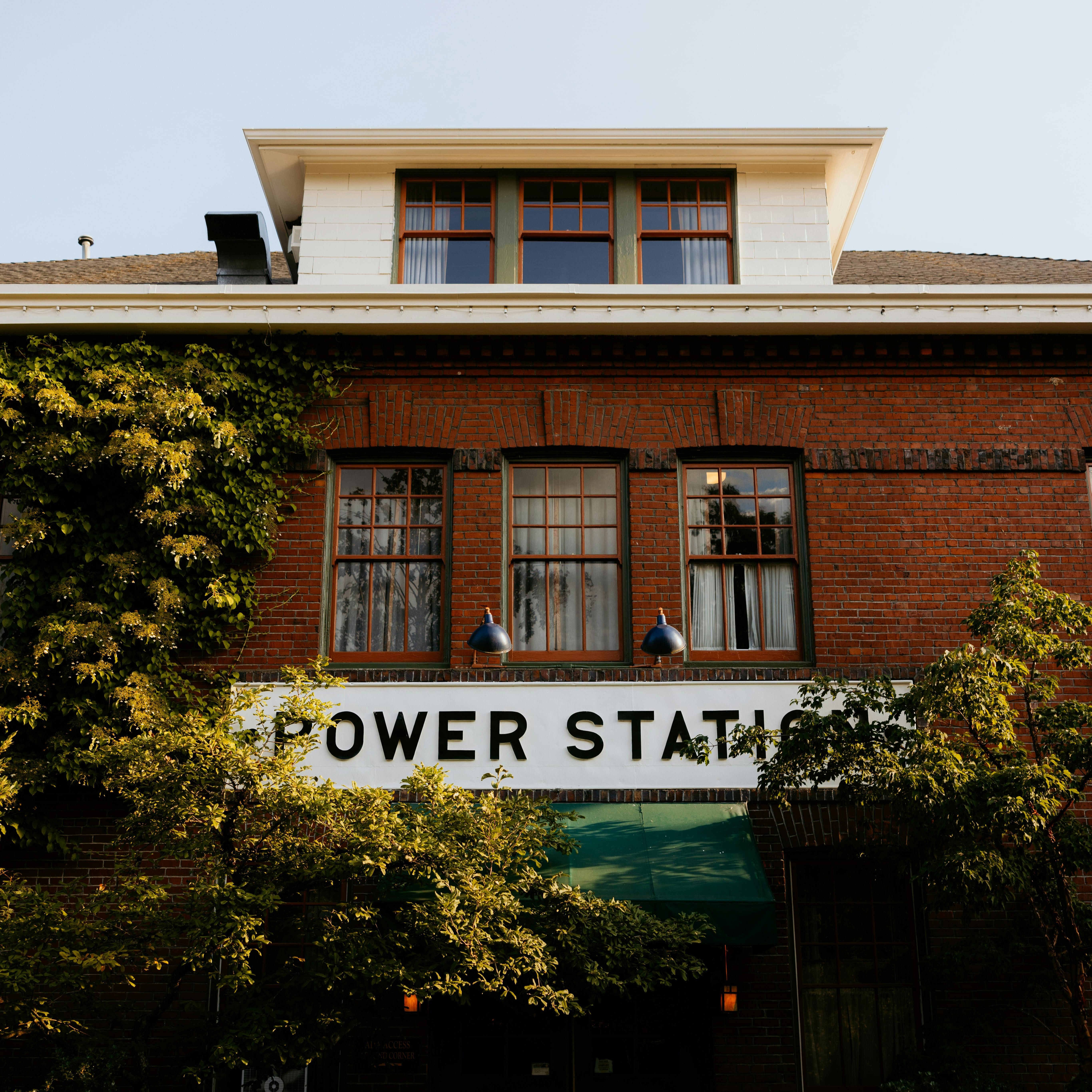 pexels-kathrinepnw-27969743 Gebäude mit der Aufschrift "POWER STATION", umgeben von Pflanzen und Fenstern, im Kontext von Wellness und Energieproduktion.