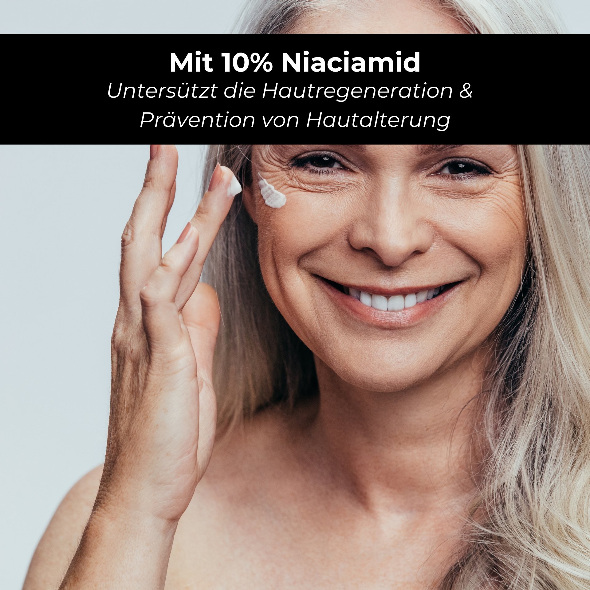 Frau mit grauen Haaren, die Niacinamid-Creme auf ihr Gesicht aufträgt, unterstützt Hautregeneration und Altersprävention, mit Text: "Mit 10% Niacinamid".